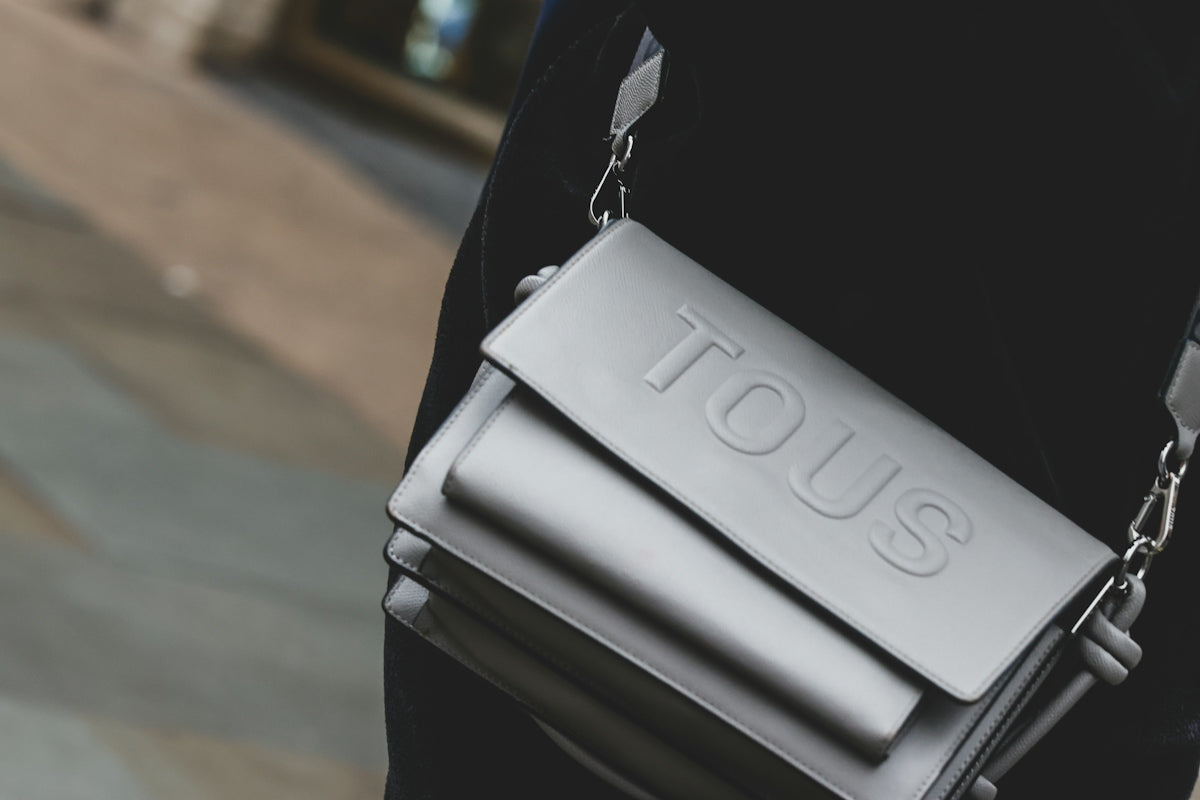 A person wearing a black shirt carrying a silver bag
